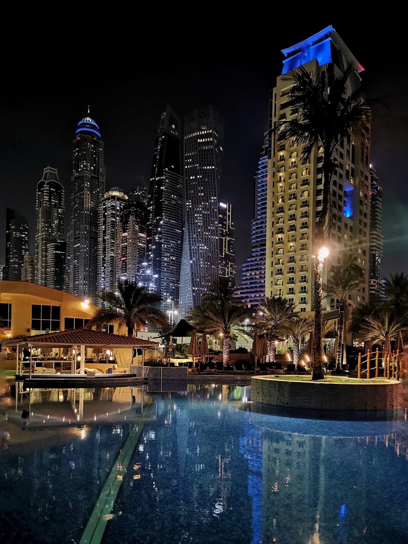 The Dubai Marina skyline at night over a pool